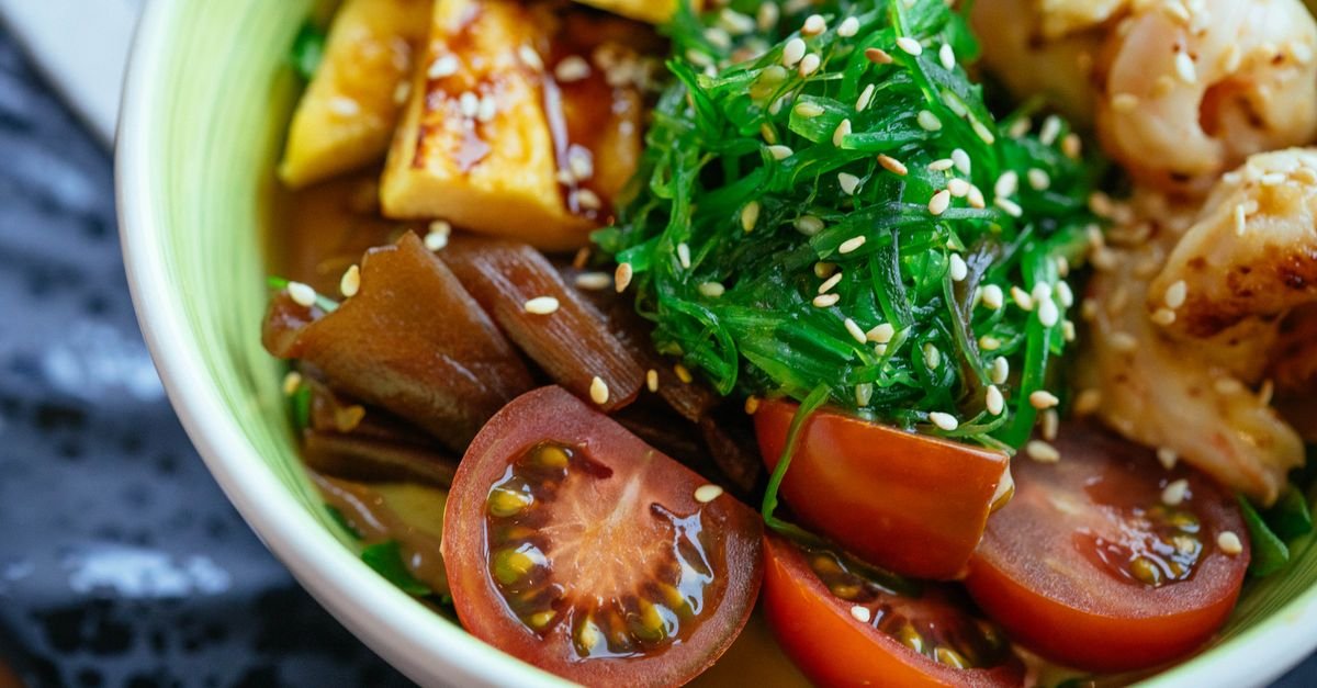A colorful vegan poke bowl with fresh vegetables, tofu, and sesame seeds.