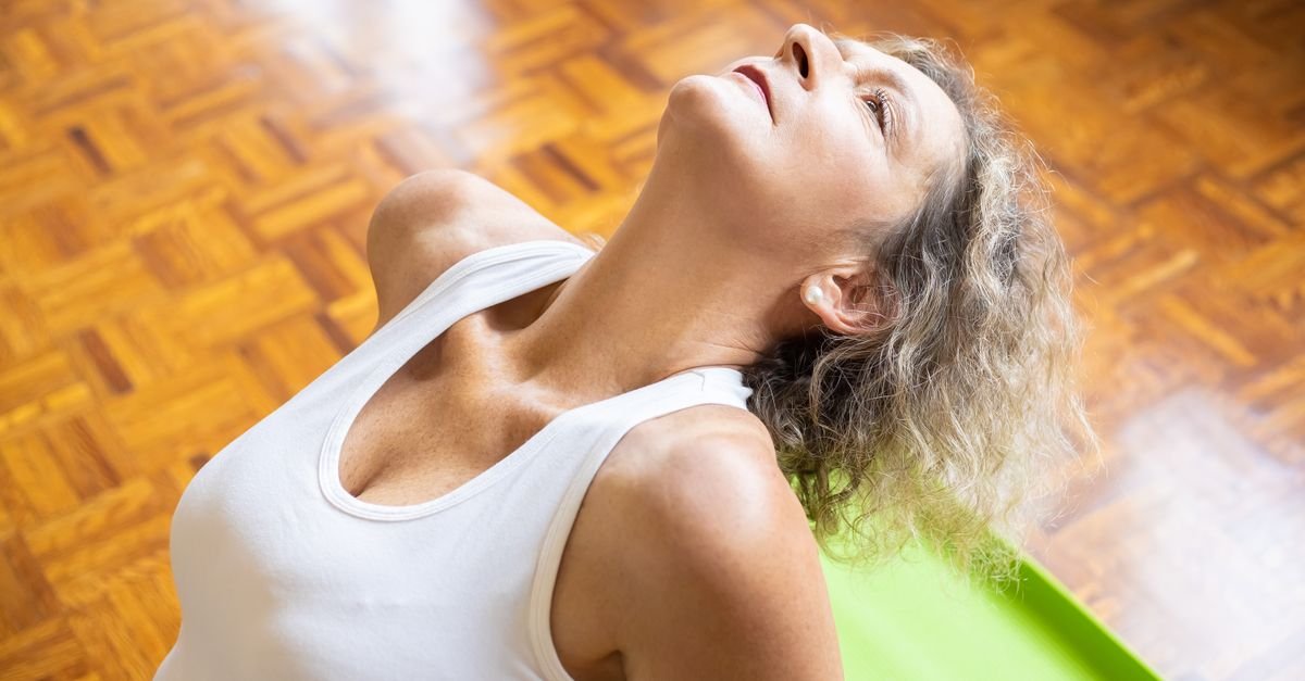 An elderly woman stretching on a yoga mat, promoting fitness and a healthy lifestyle.