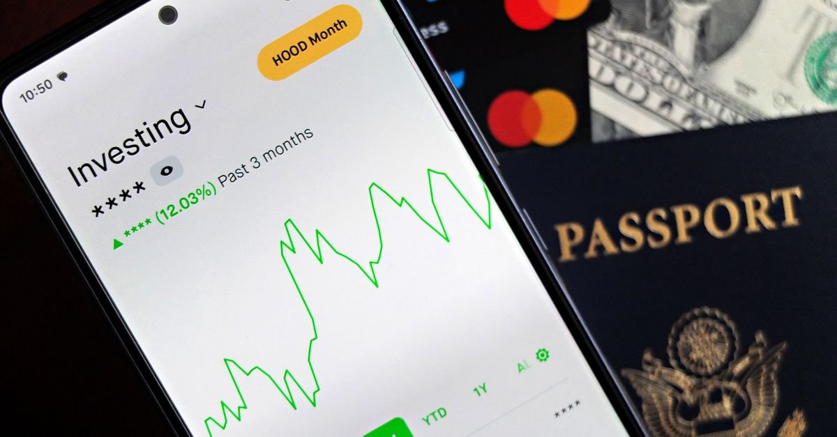 Smartphone showing stock market app with travel essentials: passport, money, and cards.