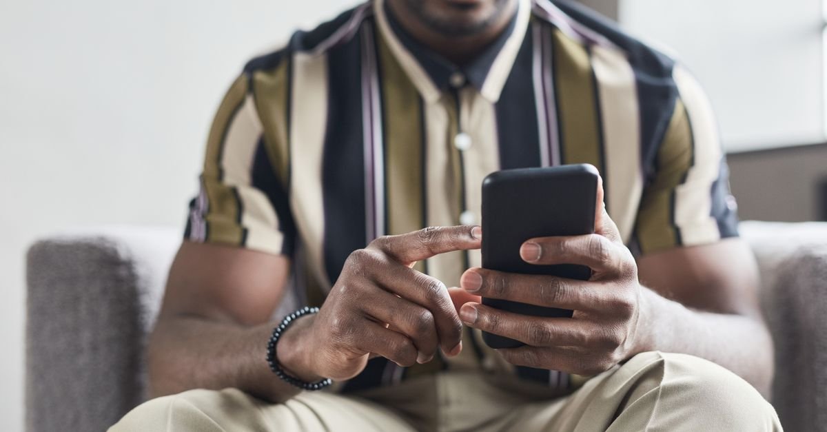 Close-up of an African American man using a smartphone indoors.