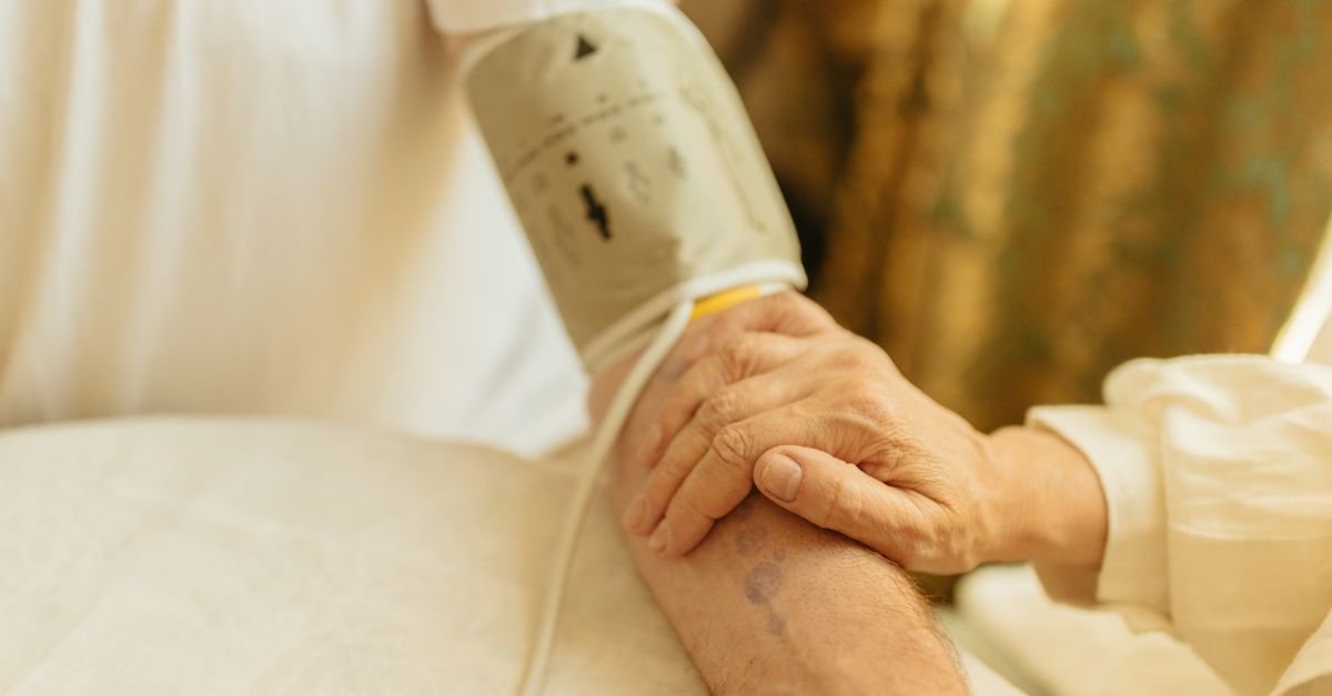 Close-up of a blood pressure measurement on a senior adult's arm indoors. Soft lighting.