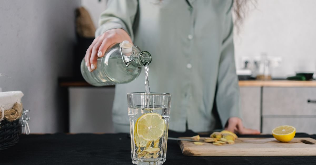 Woman pours water for lemon ginger infusion, promoting health and hydration.