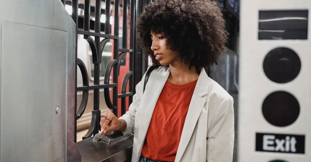 Young woman navigating a subway turnstile with a card in an urban station.