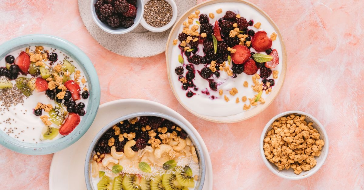 Colorful breakfast bowls featuring fresh fruits and granola on a pastel background.
